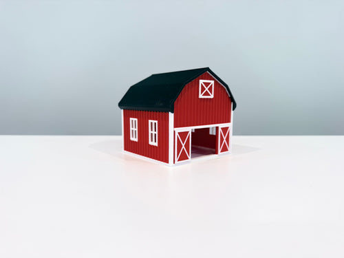 Red Barn miniature with white trim, a black roof and an open front doorway, shown from an angle.