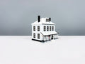 White Farmhouse miniature with a wide porch, white roof and two black chimneys, shown from an angle.