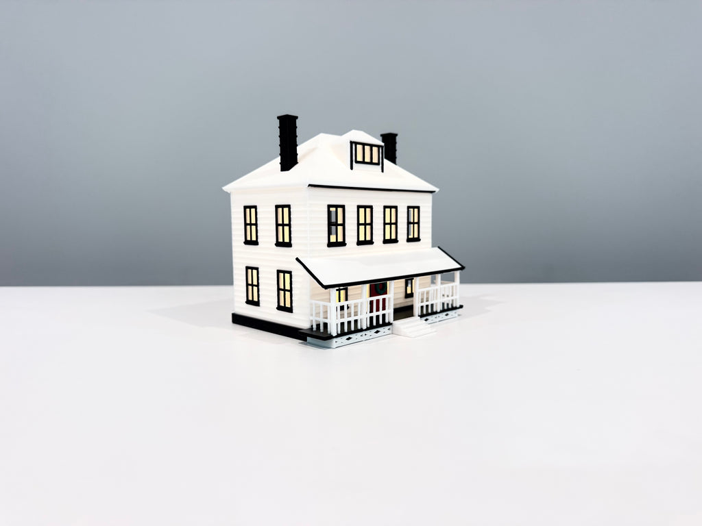 Farmhouse miniature with warm light visible through its windows.