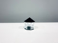 White miniature gazebo with a black roof, shown from an angle.