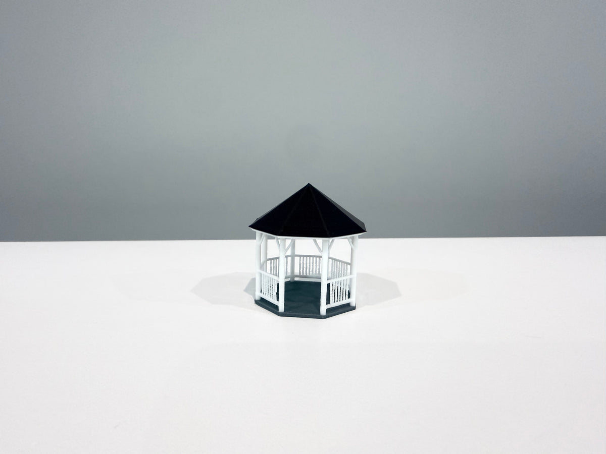 White miniature gazebo with a black roof, shown from an angle.