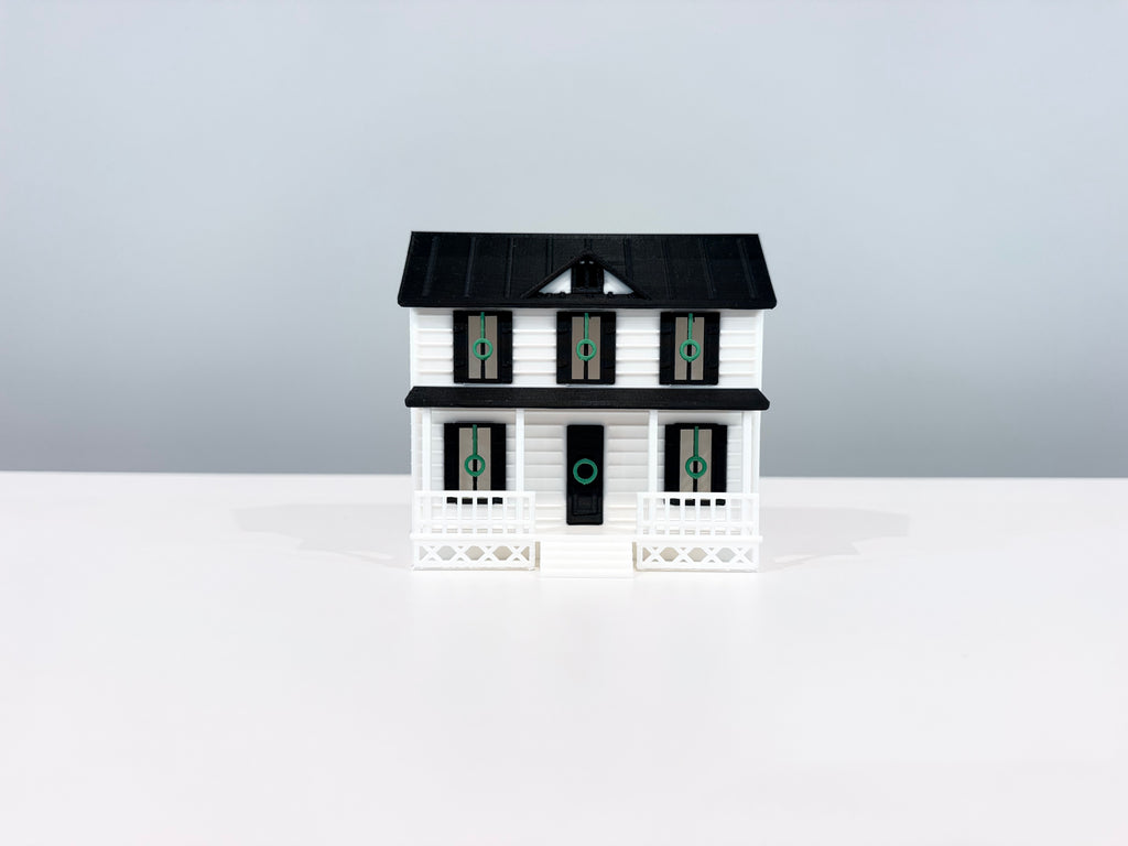 Front view of the Village House miniature with black trim and a white porch.