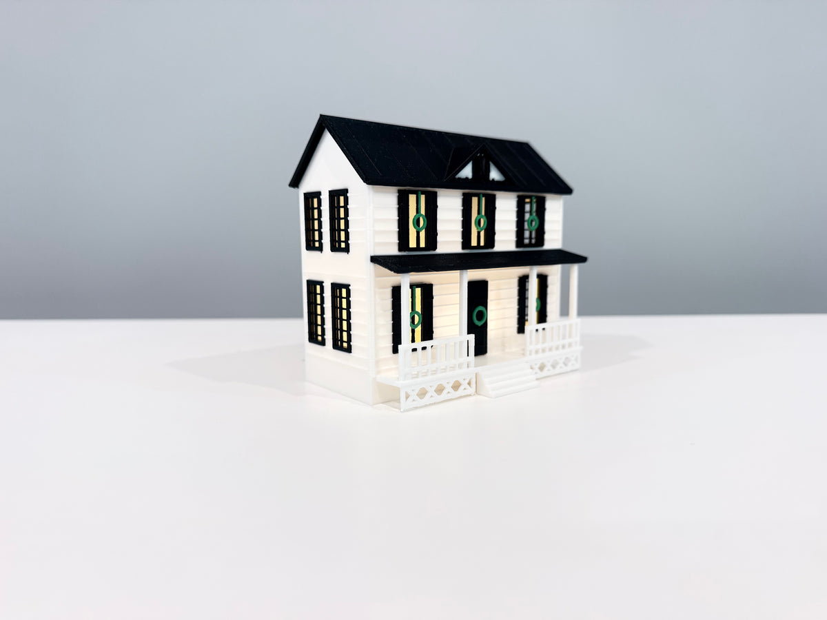 Village House miniature with warm light visible through its windows.