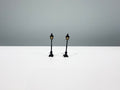 Two black miniature light posts with warm-colored lantern panels.