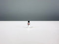 White miniature snowman wearing a black top hat and red scarf.